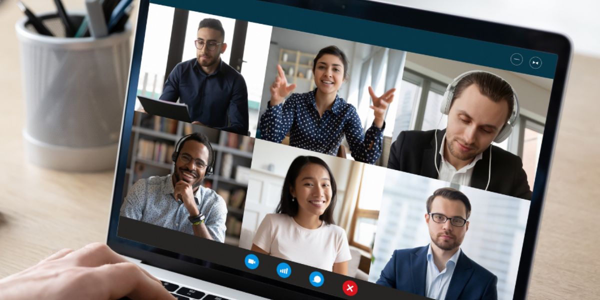 A laptop screen showing six people on a video call, talking and gesturing mid-conversation.